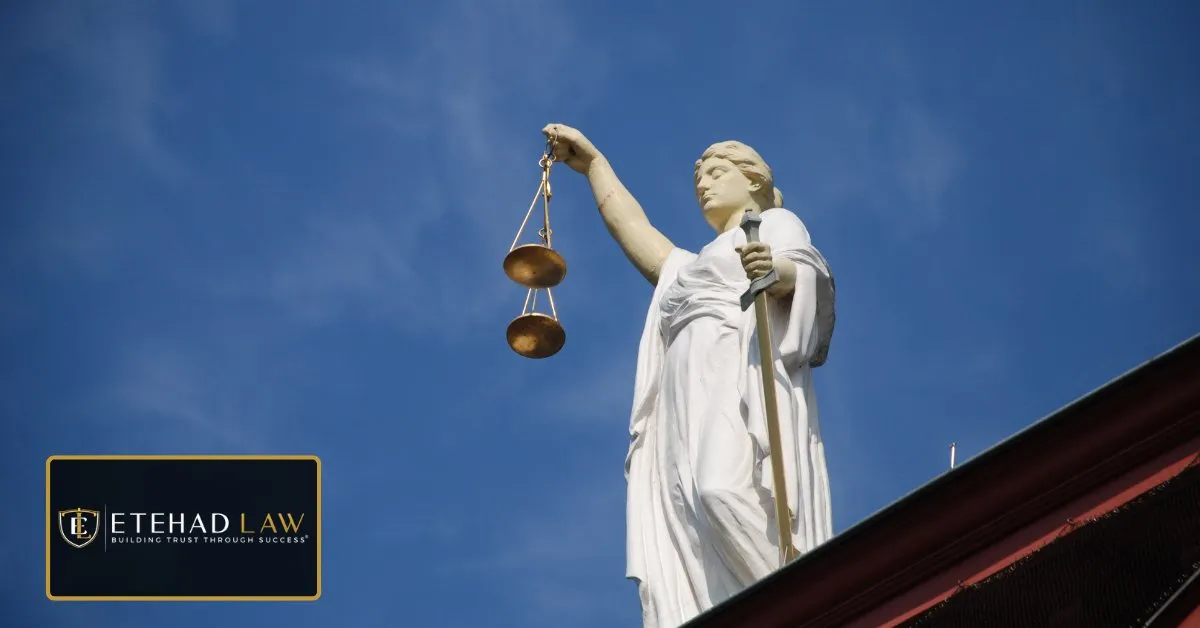 Statue of Lady Justice holding scales against a clear blue sky – Etehad Law.