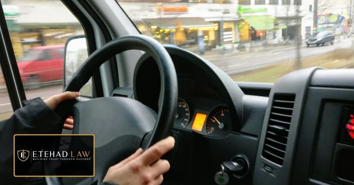 Hands on the steering wheel of a car moving through city traffic
