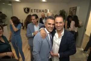 Two guests posing together under the Etehad Law crest