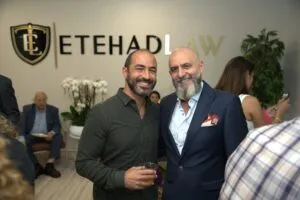Two guests posing in front of the Etehad Law wall sign
