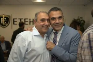 Two guests with arms around each other at the opening reception