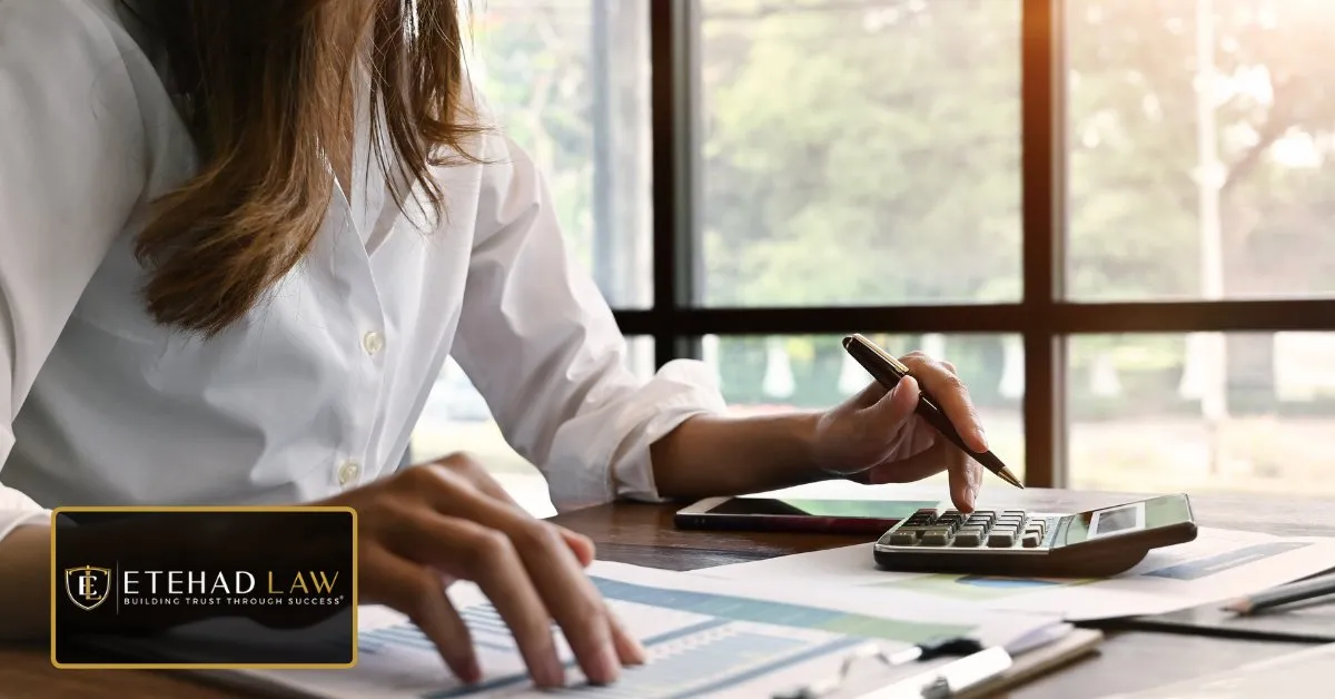 Person using a calculator and pen over financial papers at a desk, representing how a personal injury settlement is calculated