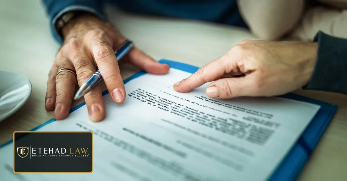 Two people reviewing insurance claim documents before signing an agreement – Etehad Law.