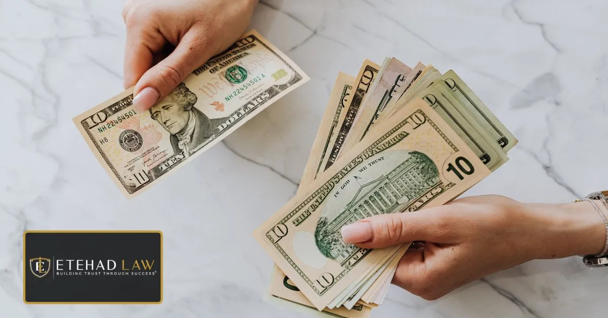 Hands holding and counting ten dollar bills on a marble table, representing compensation after a brain injury