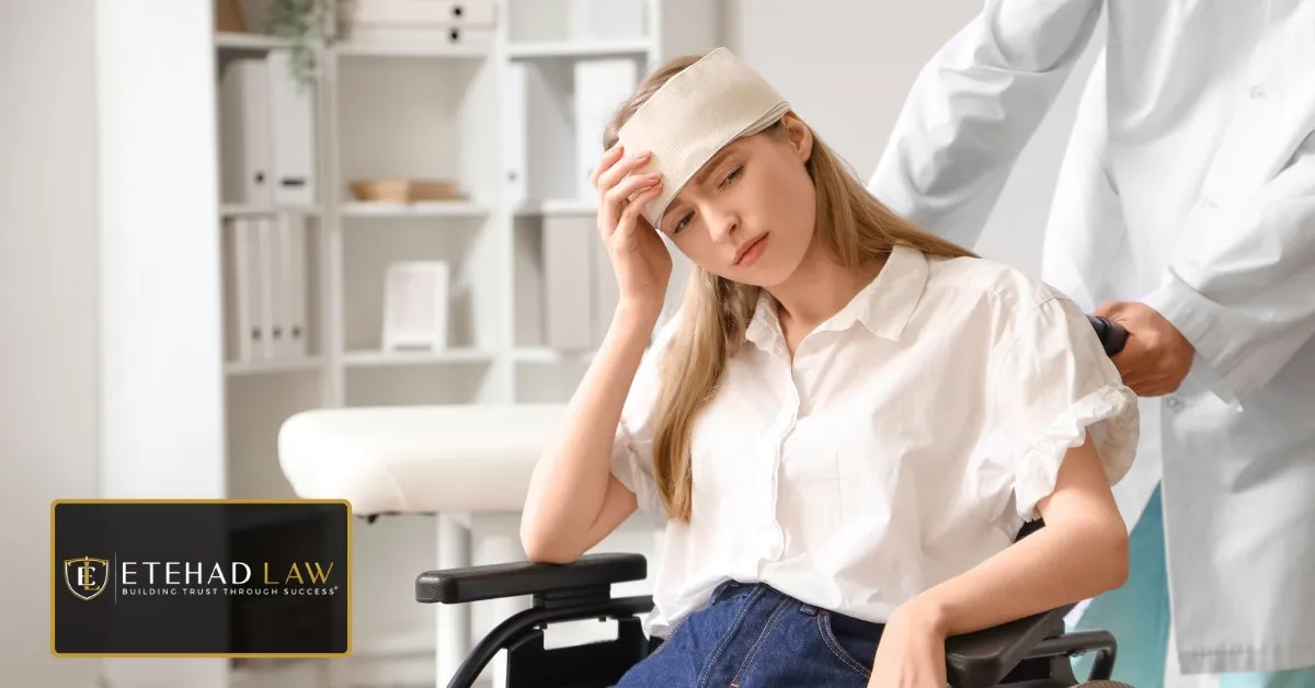 Woman with a bandaged head injury being taken through a clinic in a wheelchair by a doctor