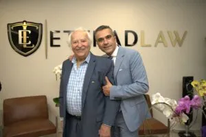 Two guests posing in front of the illuminated Etehad Law sign