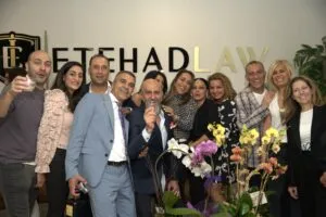 A group of guests raising a toast beneath the Etehad Law sign