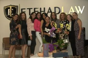 A group of women posing beneath the Etehad Law sign at the opening