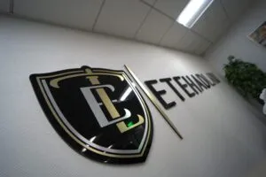 Close-up of the gold Etehad Law crest mounted on the office wall