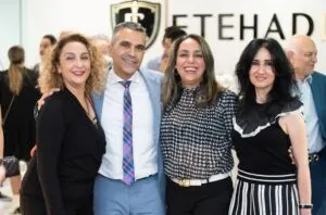 Four guests posing beneath the Etehad Law sign