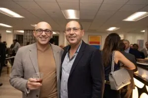 Two guests holding drinks at the opening party