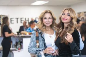 Two guests holding drinks in front of the Etehad Law sign