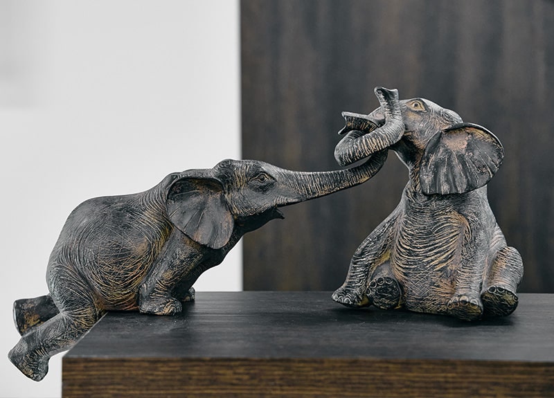 Two elephant figurines reaching toward one another — a symbol of Etehad Law's philosophy of care