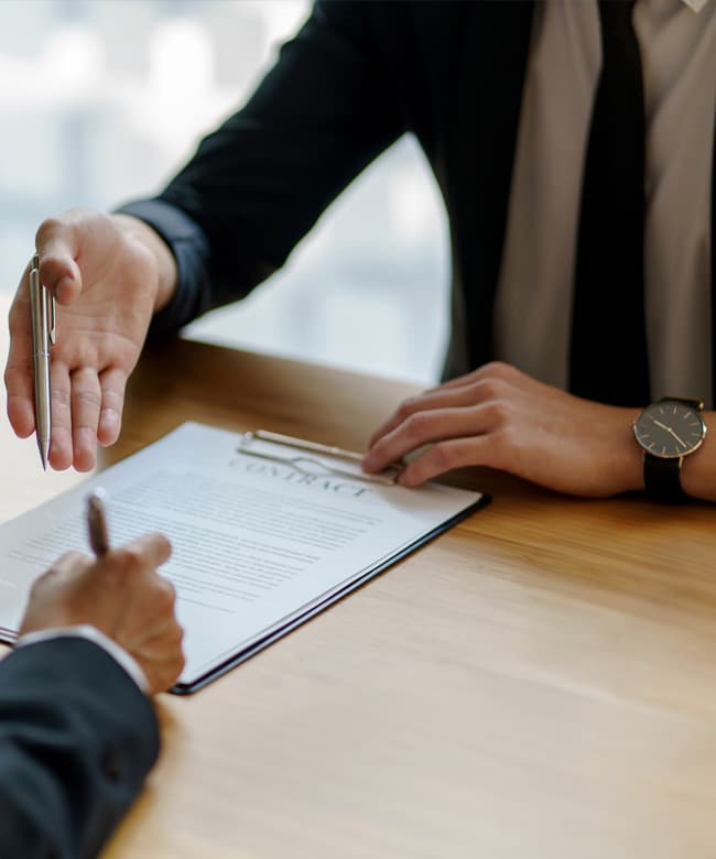 Two people reviewing and signing a contract across a desk during a business litigation consultation