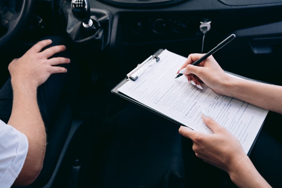Person signing an auto insurance claim form inside a car after an accident